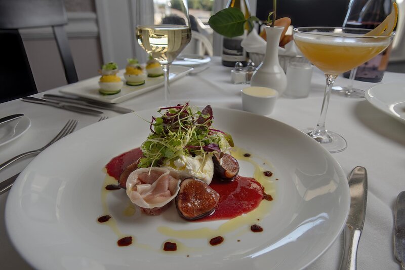 Burrata, Prosciutto, Marinated Figs, Arugula, Saba appetizer with cocktail and white wine