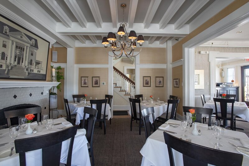 Dining room with set tables with white clothes and view of fireplace